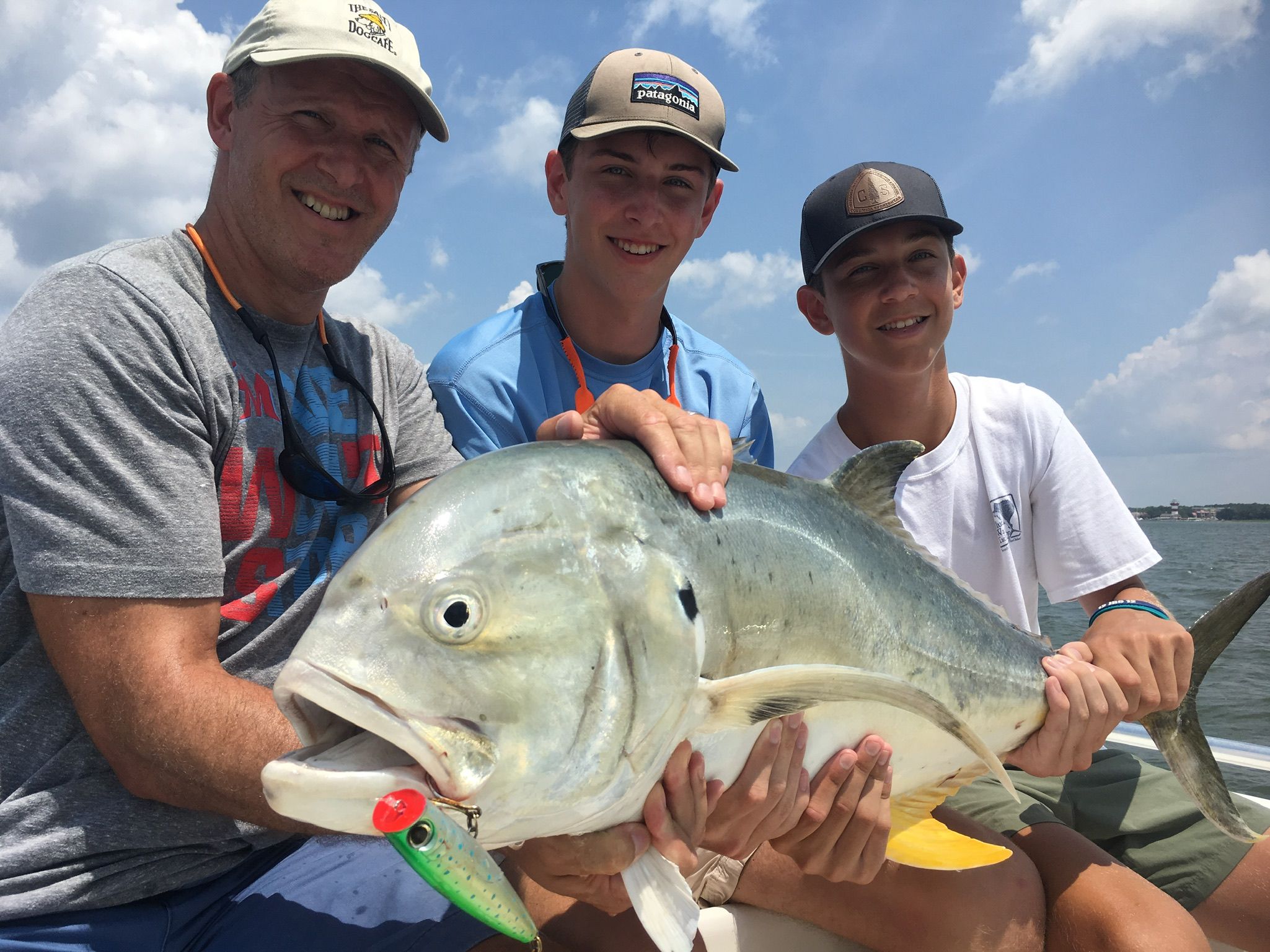 Father and two teens holding a large jack crevalle