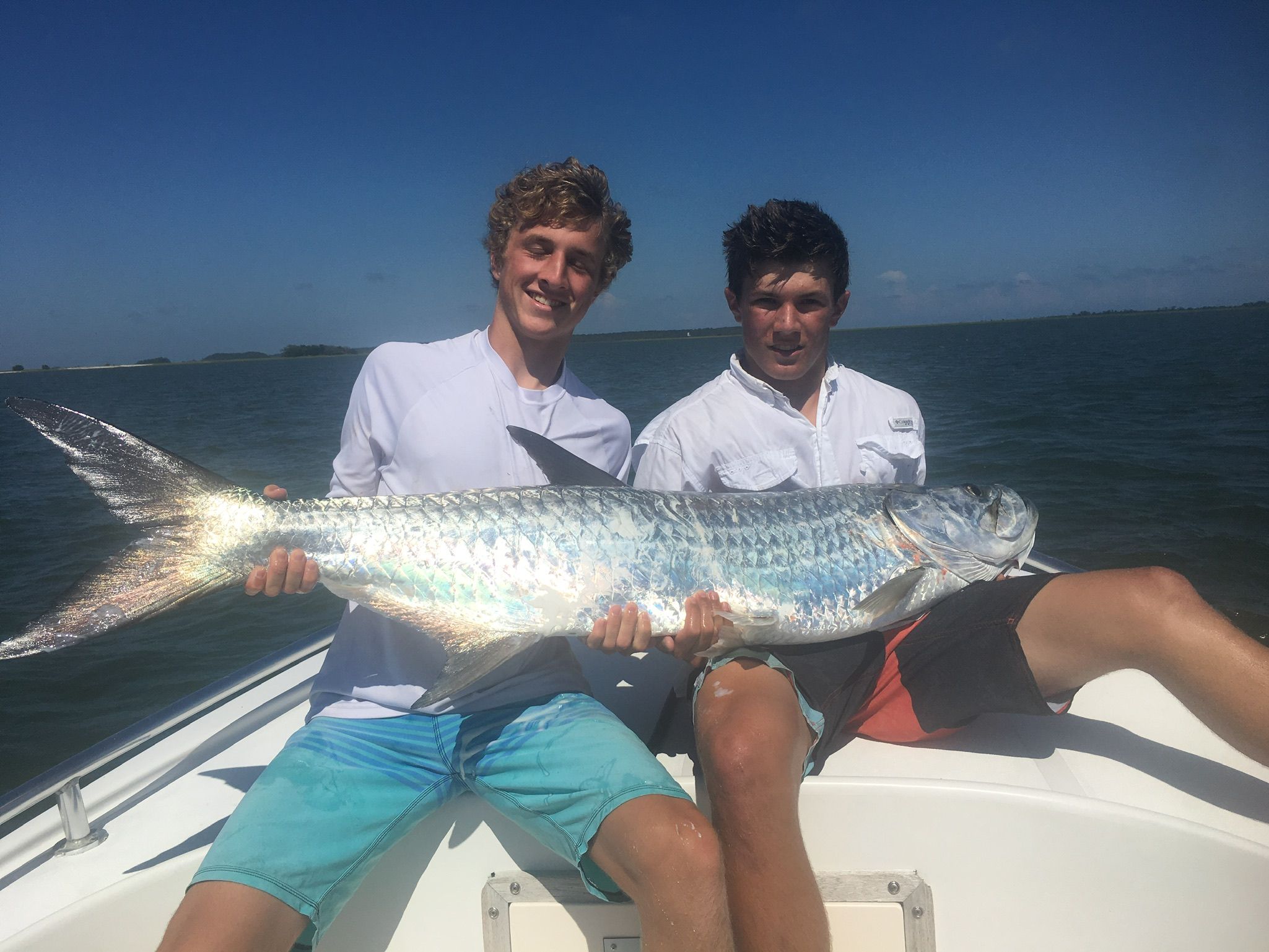 Two young anglers holding a tarpon on the boat