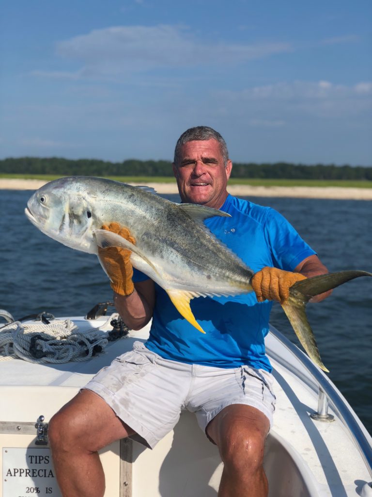 Angler holding a jack crevalle over the water