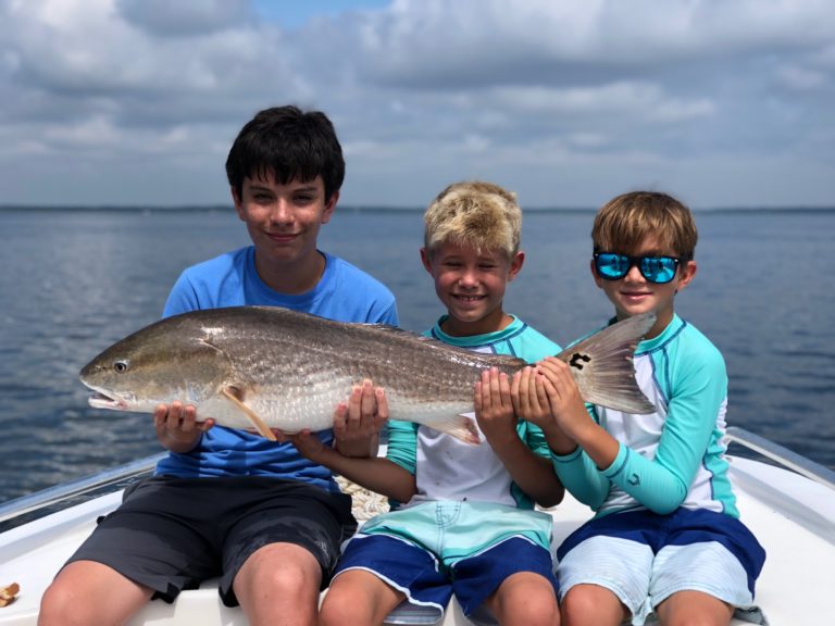 Three kids holding a redfish on a Hilton Head fishing charter