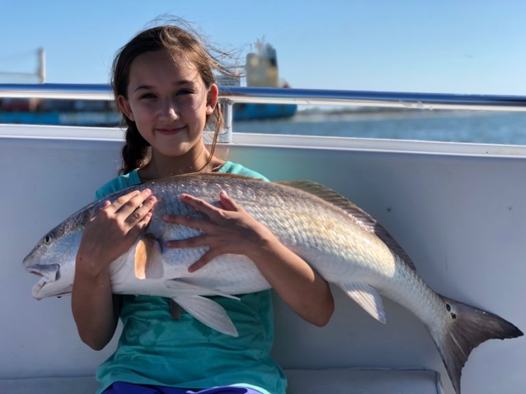 Girl holding a redfish on the boat