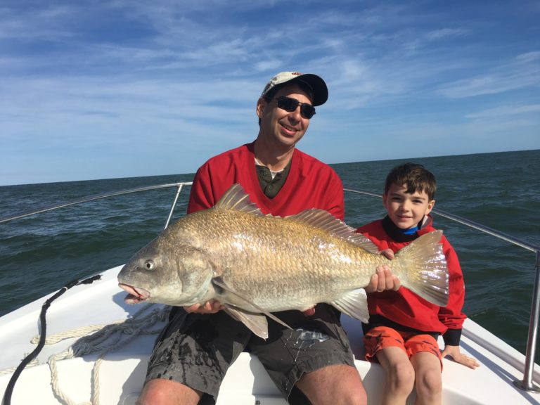 Father and son holding a black drum on the bow