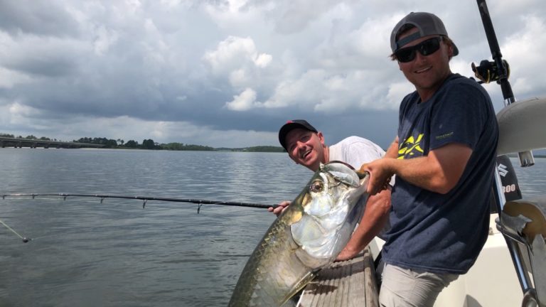 Two anglers with a tarpon alongside the boat