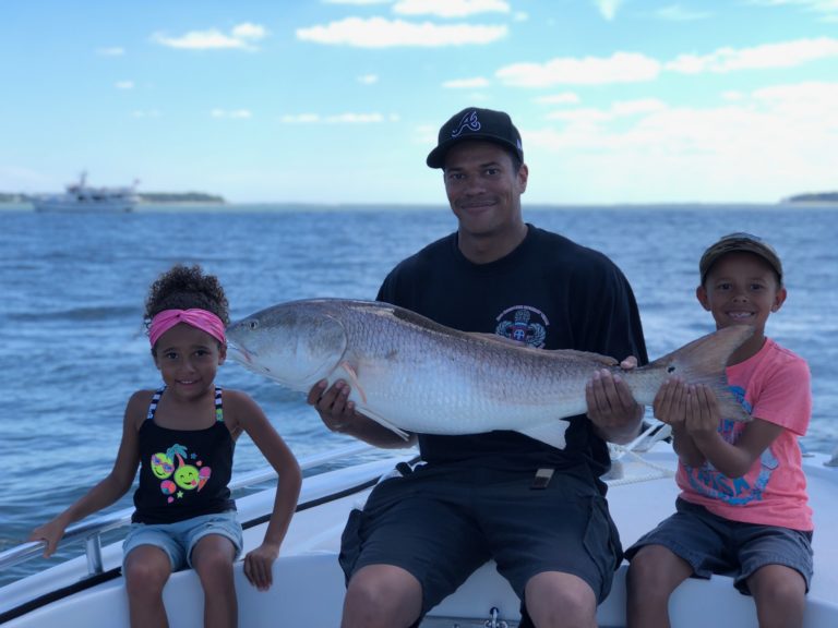 Dad and two kids with a big redfish on a family fishing charter
