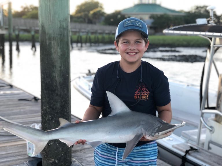 Boy holding a shark on the dock after a charter