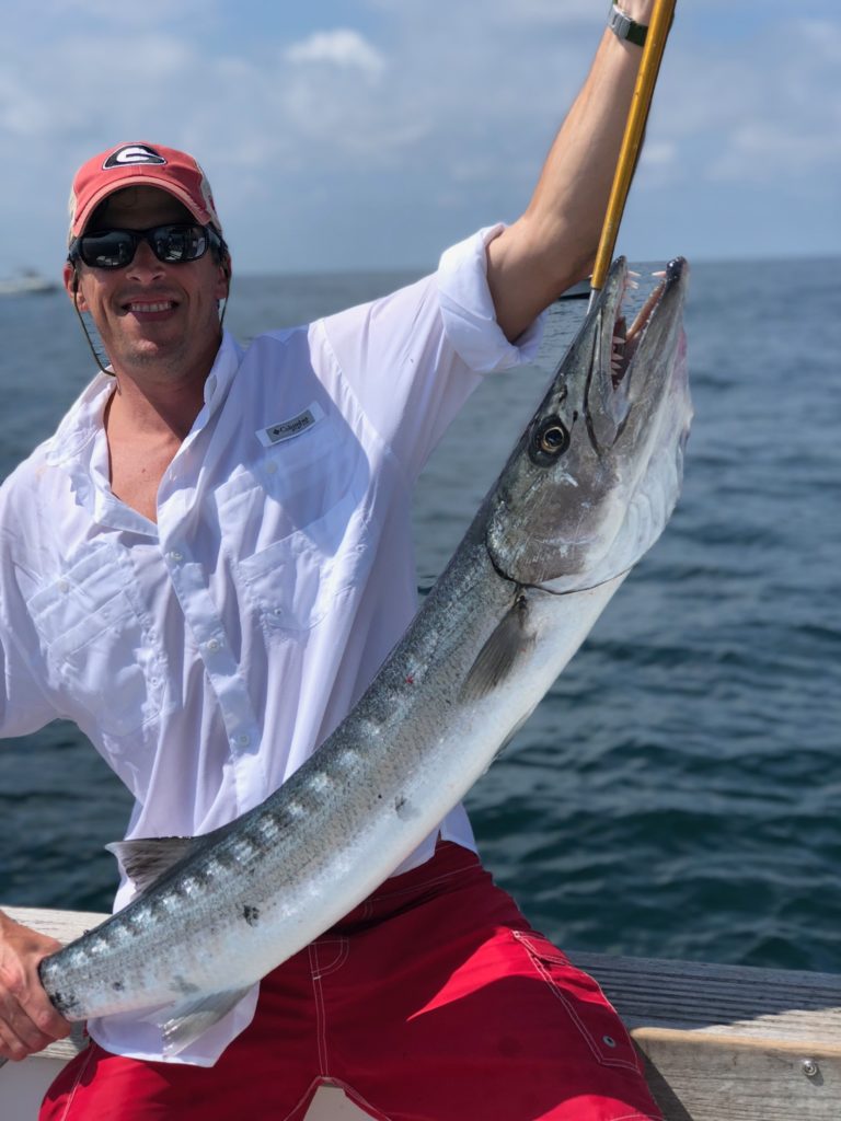 Angler lifting a long silver fish caught nearshore off Hilton Head