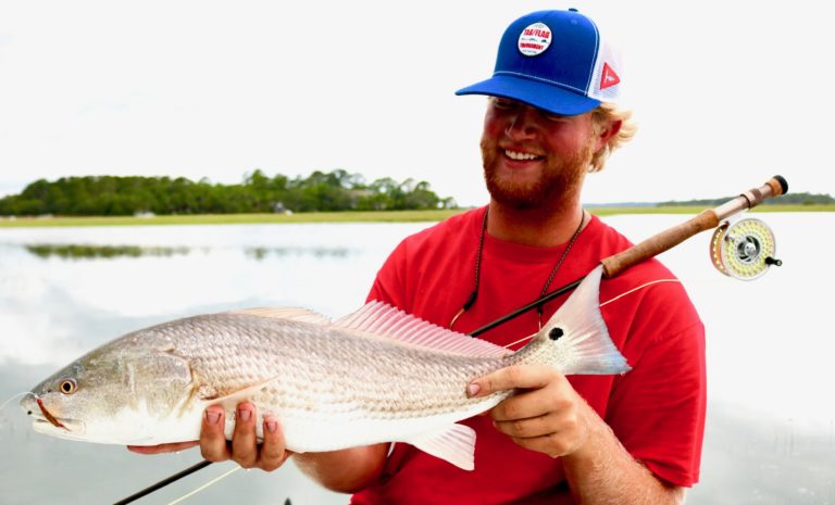 Fly angler holding a redfish caught on the flats