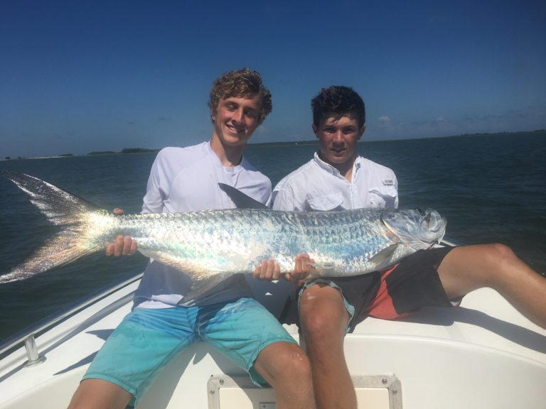 Two young anglers holding a tarpon on the boat