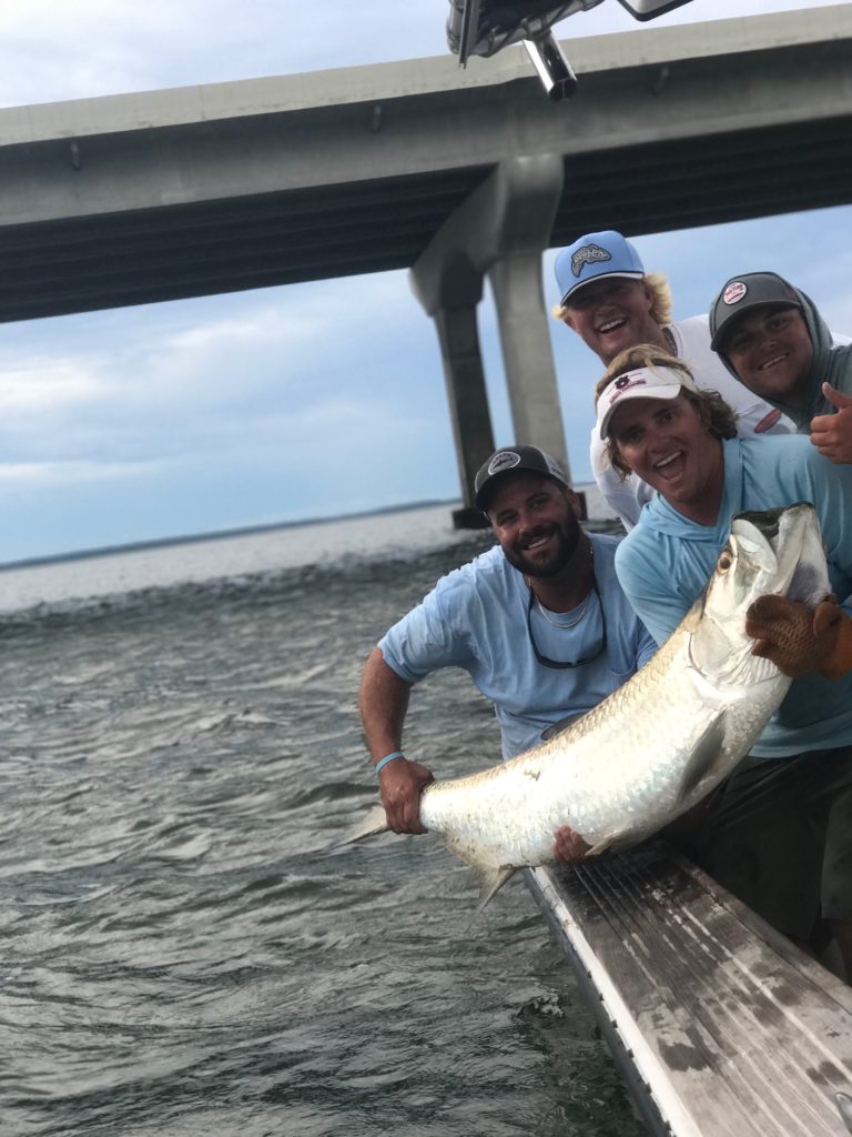 Group of anglers with a tarpon beside the boat near the bridge