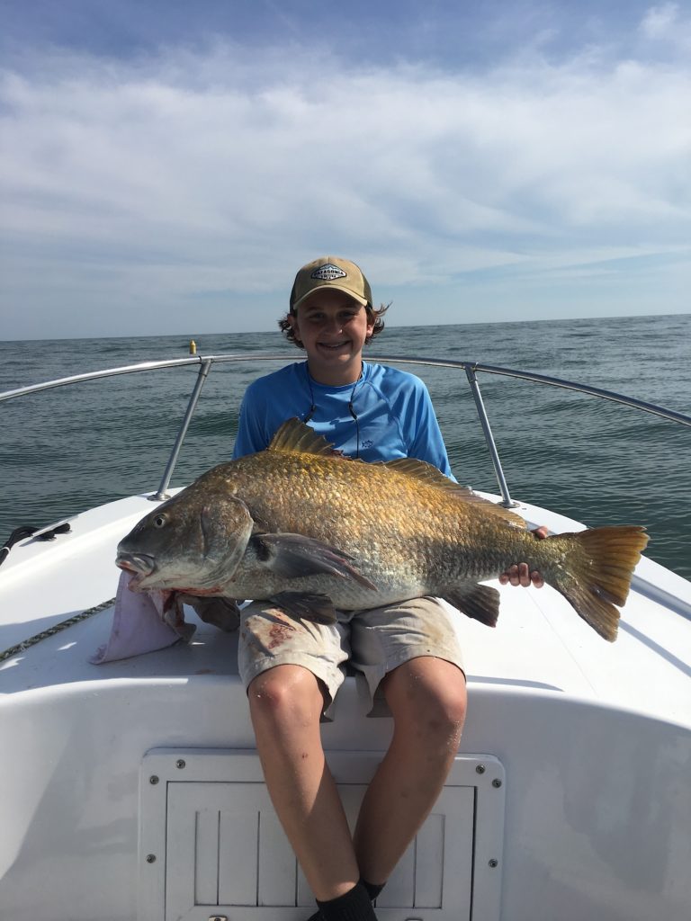 Young angler with a black drum on the boat
